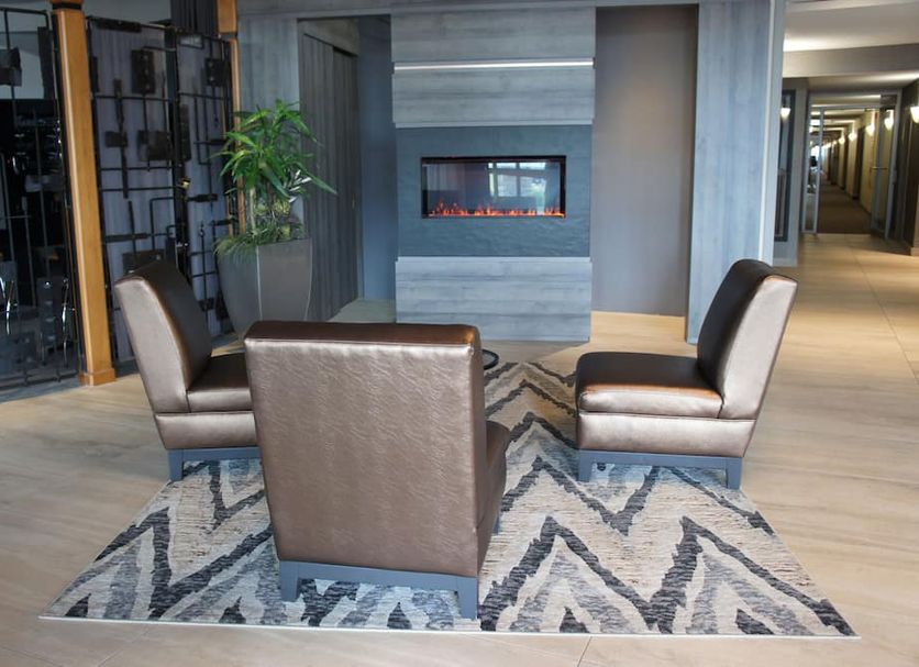 Hôtel Castel in Granby lobby with three lounge chairs on a patterned rug beside a modern fireplace