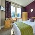 Kents Hill Park Training & Conference Centre room in Milton Keynes with double bed, desk, wardrobe and purple accent wall