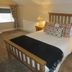 The Kings Head in Meifod: bedroom with wooden bed, bedside lamps, and a window with patterned curtains.