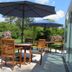 Hotel zum Rosenteich in Bad Zwischenahn: patio tables with umbrellas beside a lush garden