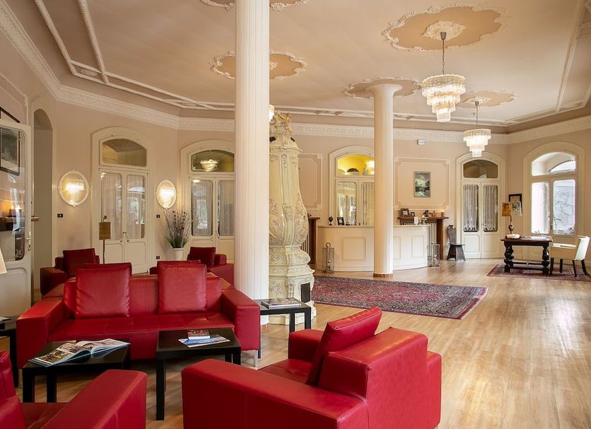 TH Borca di Cadore - Park Hotel Des Dolomites lobby with red sofas, ornate columns and wood floors in Borca di Cadore