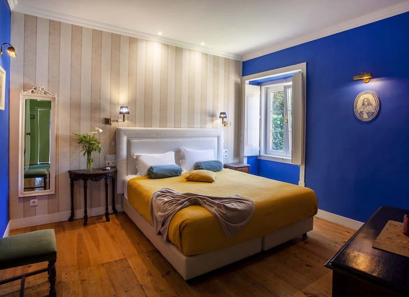 Palácio de Sintra Boutique House room in Sintra with yellow bed, blue accent wall and window