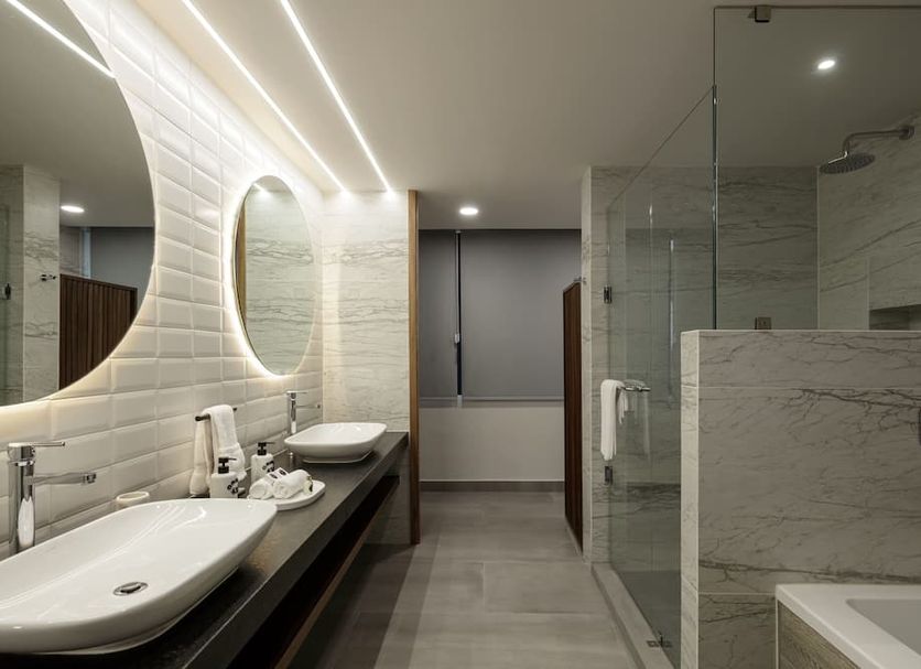 Origen 438 Luxury Boutique Hotel in Guadalajara bathroom with double sinks, lit mirror and glass shower