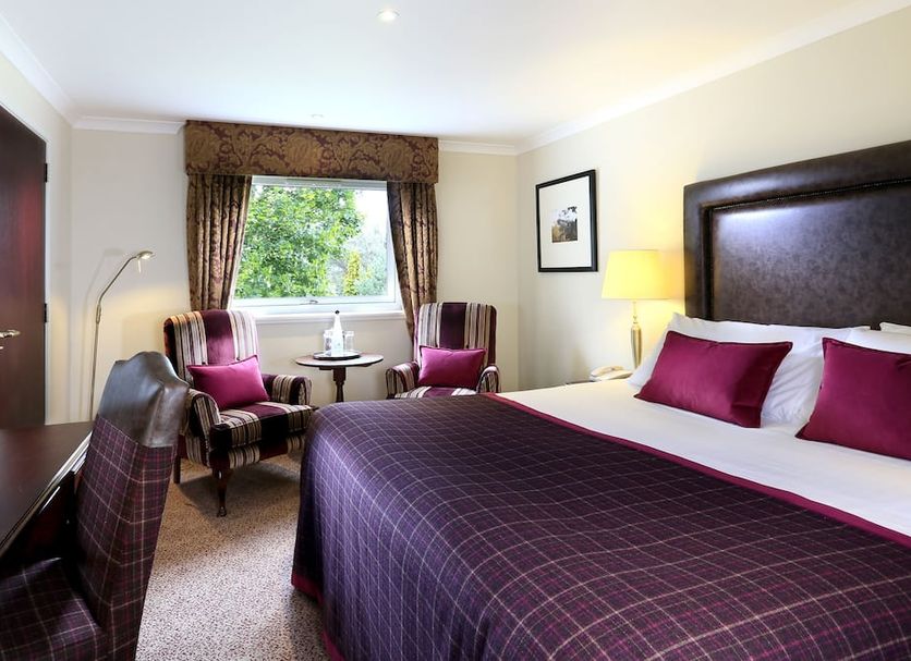 Macdonald Aviemore Highland Hotel room in Aviemore with plaid bed, armchairs and window view