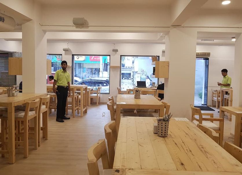 The Unicontinental - Campus Accommodation in Mumbai dining area with wooden tables and staff inside