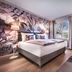 Steigenberger Hotel Treudelberg in Hamburg guest room with floral accent wall, bed, lamps and window view
