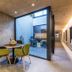 Hotel Lener in Mauls: covered patio dining nook with round table, yellow chairs and glass doors to a courtyard