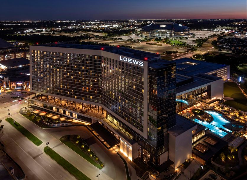Loews Arlington Hotel at night with illuminated exterior and rooftop pool overlooking Arlington