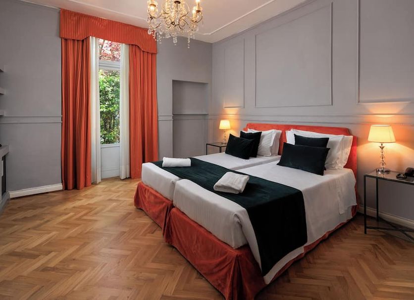 Hotel Villa Carlotta in Florence: elegant bedroom with king bed, chandelier, parquet floor, and French doors to balcony