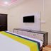 Hilltown Hotel in Madikeri guest room with two chairs, wall-mounted TV and bed with colorful runner