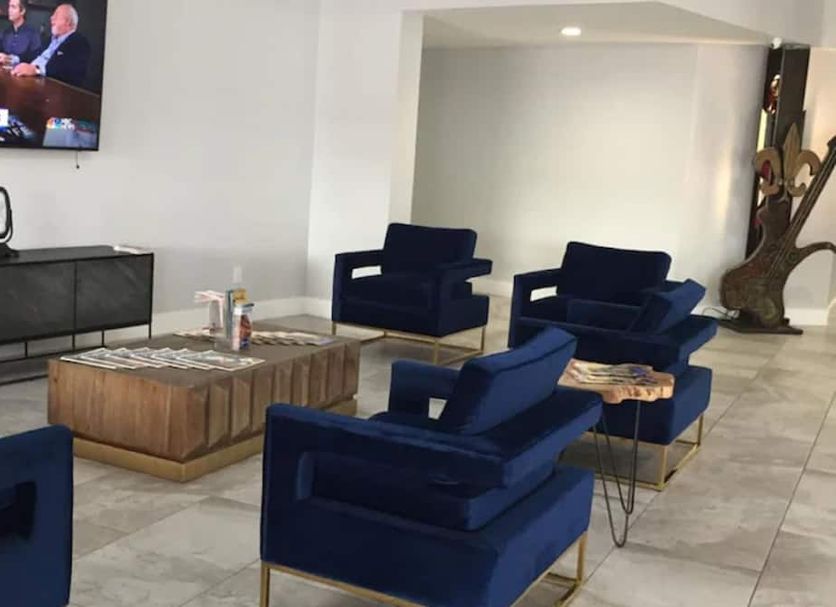 Midtown Hotel New Orleans lobby seating area with navy chairs, coffee tables and wall-mounted TV in New Orleans