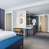 Hyatt Regency London Stratford guest room with bed, desk, and open wardrobe in London