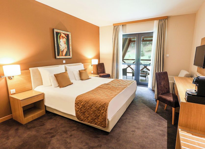 Etno Naselje Vrdnicka Kula guest room in Vrdnik with king bed, desk, and balcony door