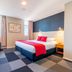 The Grosvenor Timaru guest room with king bed, red throw, seating area and checkerboard carpet