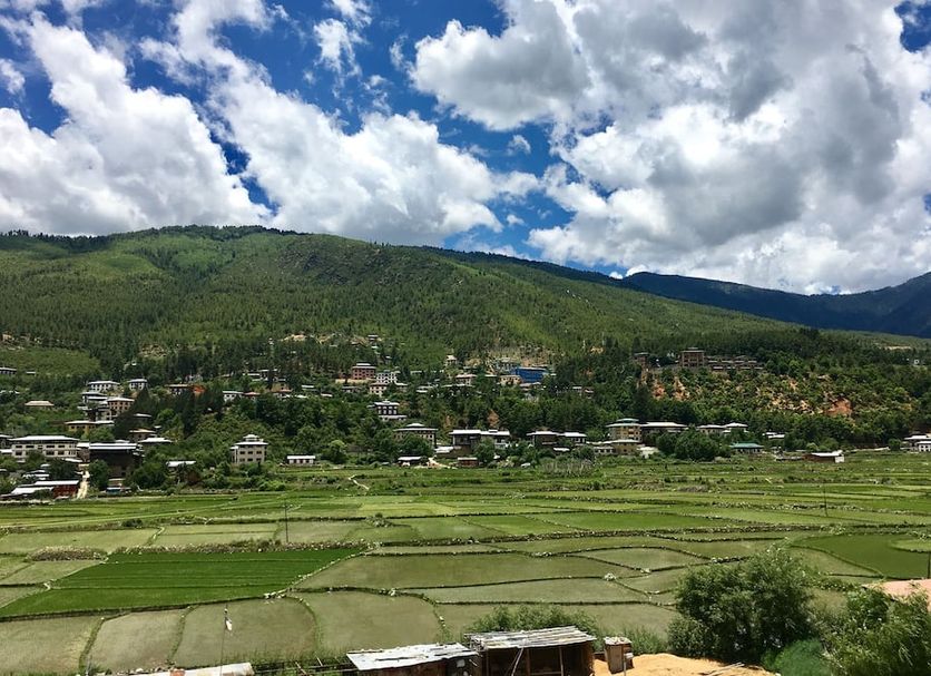 Hotel Khamsum in Paro with scenic valley, terraced fields, and mountain views under a cloudy sky