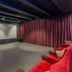 Finns Paekakariki screening room with projector screen, red seating and burgundy curtains in Paekakariki