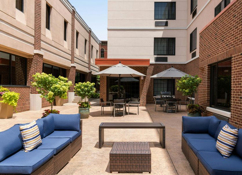 TownePlace Suites by Marriott Williamsport courtyard with blue lounge seating and umbrella tables
