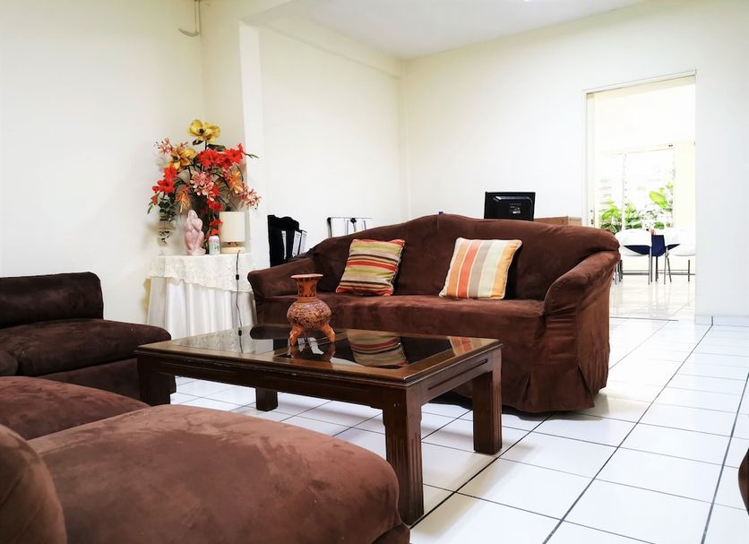 Hotel Armonía Hostal lounge in San Salvador with brown sofas, glass coffee table and tiled floor