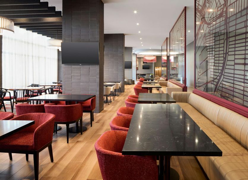 Residence Inn by Marriott Montreal Airport lounge with red chairs, tables and banquette seating in Montreal