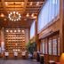 Lijiang Tianyu Boutique Hotel lobby with wooden beams, chandelier, wine display, and tall windows