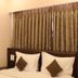 Hotel Sunny International in Mahabaleshwar guest room with bed, pillows, and curtained window