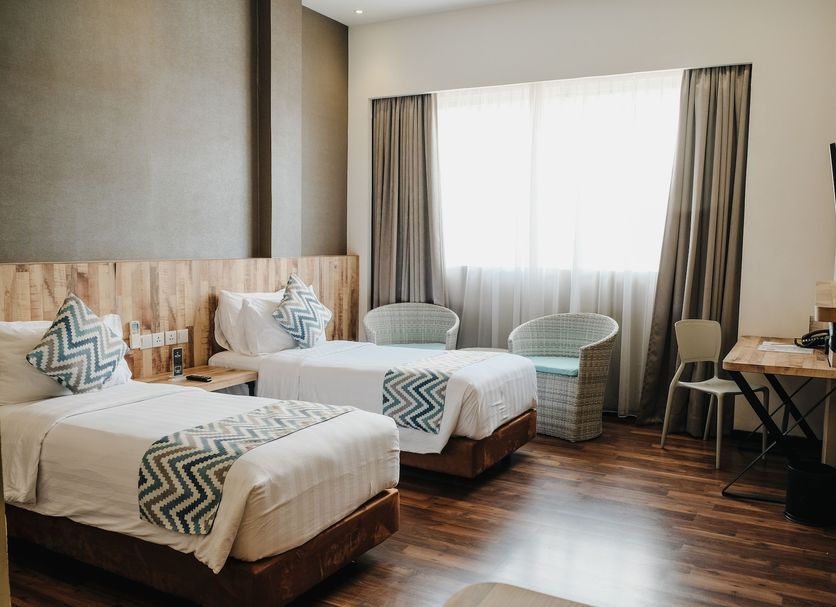 All Nite And Day Palembang Veteran room with two single beds, desk, chairs, and large window