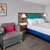 Hampton Inn Kansas City The Legends guest room with king bed, armchair, and bedside lamps