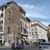 Suite Art Navona in Rome, street view of a historic corner building with parked cars and scooters