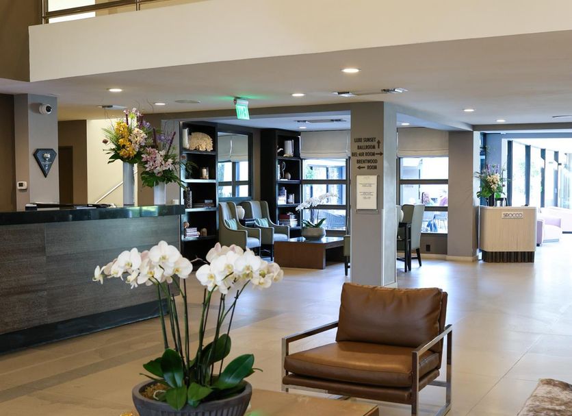 Luxe Sunset Boulevard Hotel lobby in Los Angeles with seating area, reception desk, and mezzanine balcony