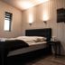 Afternoon Cottages in Hella bedroom with black bed, wood-paneled walls, bedside lamp, and armchair