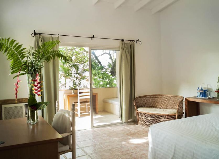 Cormier Plage Resort in Cap Haitien guest room with sliding doors to a balcony and wicker chair
