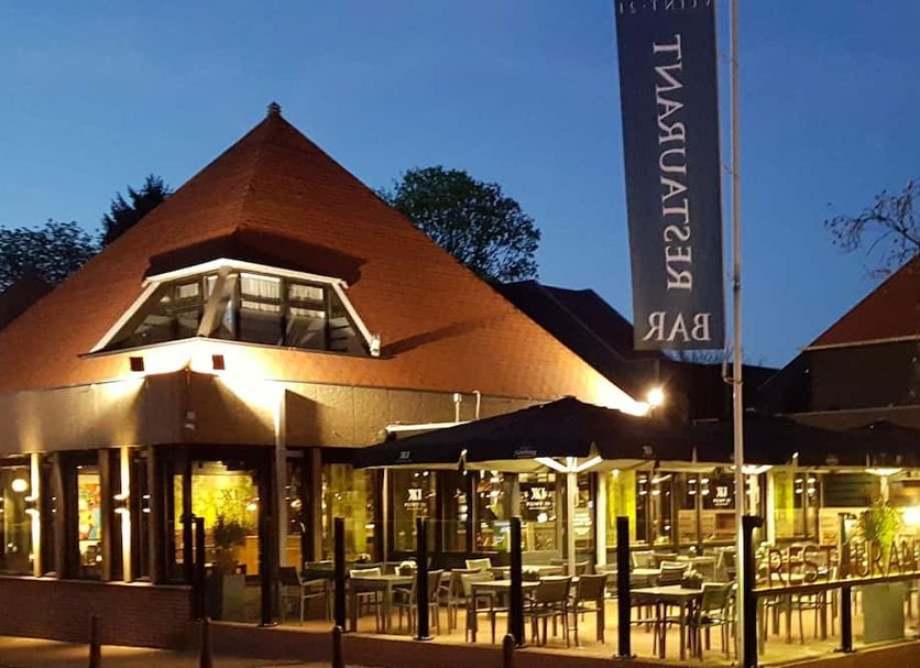 Hotel Bieze in Borger at dusk, with a warmly lit outdoor terrace and steep-roofed building