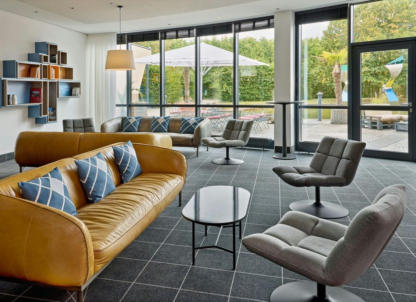 Four Points Flex by Sheraton Ratingen Düsseldorf Airport lounge with seating and large windows in Ratingen