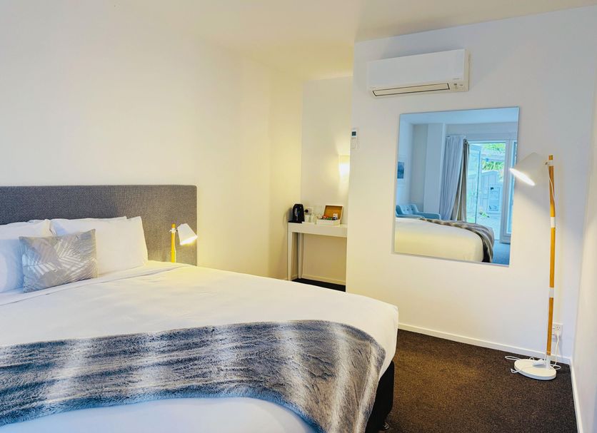 Franz Josef Oasis room with king bed, wall mirror, desk and floor lamp in Franz Josef Glacier