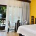 Iara Beach Hotel Boutique in Salvador, guest room with bed, balcony door, and oceanfront greenery view
