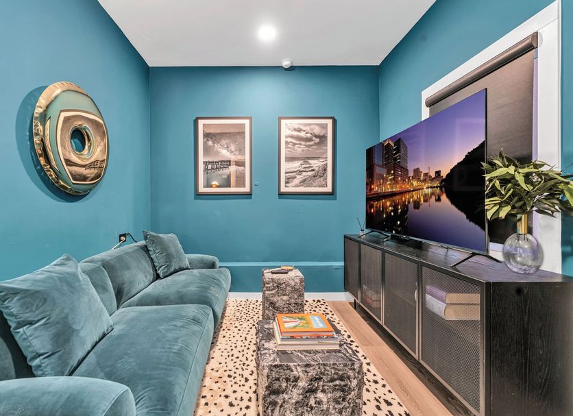 Hotel Zindel San Diego living room with teal walls, sectional sofa, TV console and decorative wall art