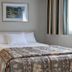 Vagabond Inn Ventura guest room with queen bed, bedside lamp, framed art, and striped curtains in Ventura.