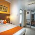 Hotel Poncowinatan - Tugu, Yogyakarta guest room with double bed, orange accents, and balcony access