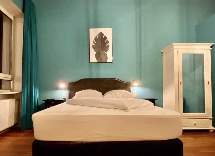 Hotel Mystique in Bad Homburg guest room with teal walls, carved ceiling, bed and white wardrobe