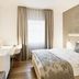 Hotel Uzwil in Uzwil: modern guest room with bed, desk, chair and window with curtains