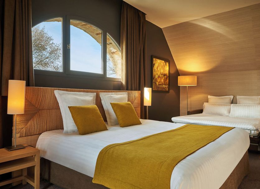 Chateau De Villiers-Le-Mahieu bedroom with king bed, arched window and mustard accents in Villiers-Le-Mahieu