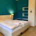 Gästehaus Seewarte Flensburg guest room with double bed, teal accent wall, and bedside lamps