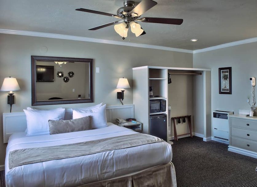 Lovers Point Inn in Pacific Grove guest room with king bed, open closet, dresser and ceiling fan