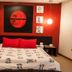 Tri Hotel Executive Caxias room with red accent wall, bed, and hanging pendant lights in Caxias do Sul