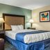 Regency Inn & Suites New London Mystic guest room with king bed, armchair, and lamps in New London