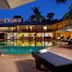 Bamboo Beach Hotel & Spa in Patong with a lit outdoor pool, palm trees and lounge chairs at dusk