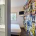 Hotelf1 Bordeaux Nord Lormont room with sink, shower, bed, and colorful collage wall in Lormont