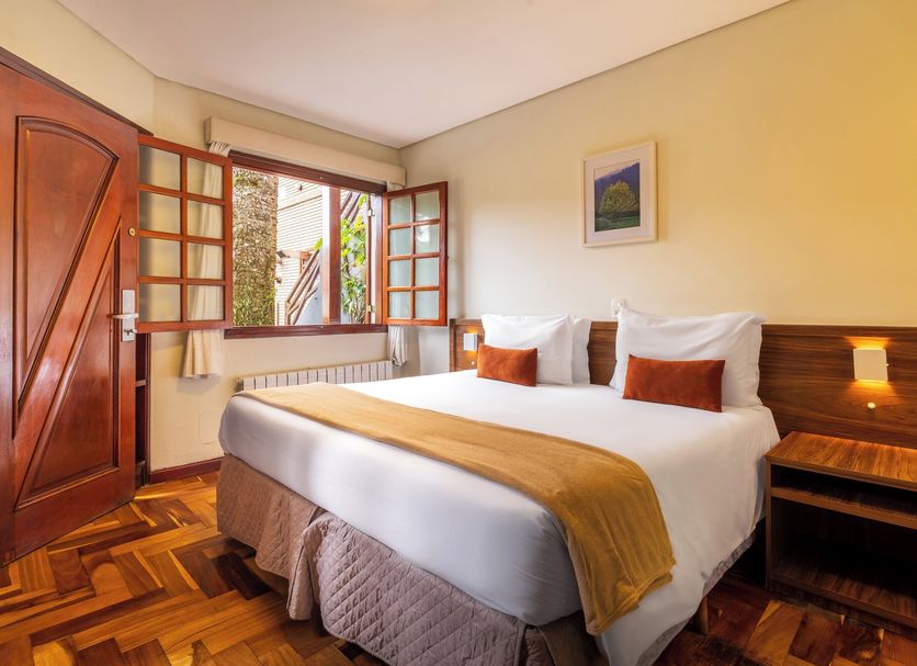 Pousada Campos de Provence room in Campos do Jordão with double bed and open window view