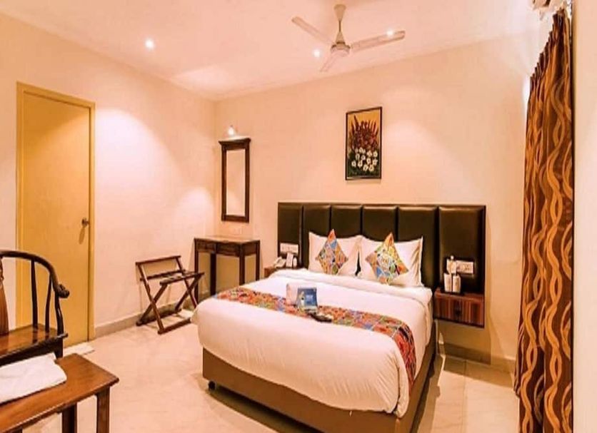 FabHotel Blossom T Nagar in Chennai bedroom with double bed, ceiling fan, chair and wall mirror