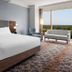 Horseshoe Tunica guest room with king bed, lounge chair, and large window overlooking greenery in Tunica Resorts